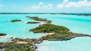 An aerial view of a tropical island with clear turquoise waters and scattered vegetation. - Tree House Atmosphere on Chalk Sound National Park (Providenciales)