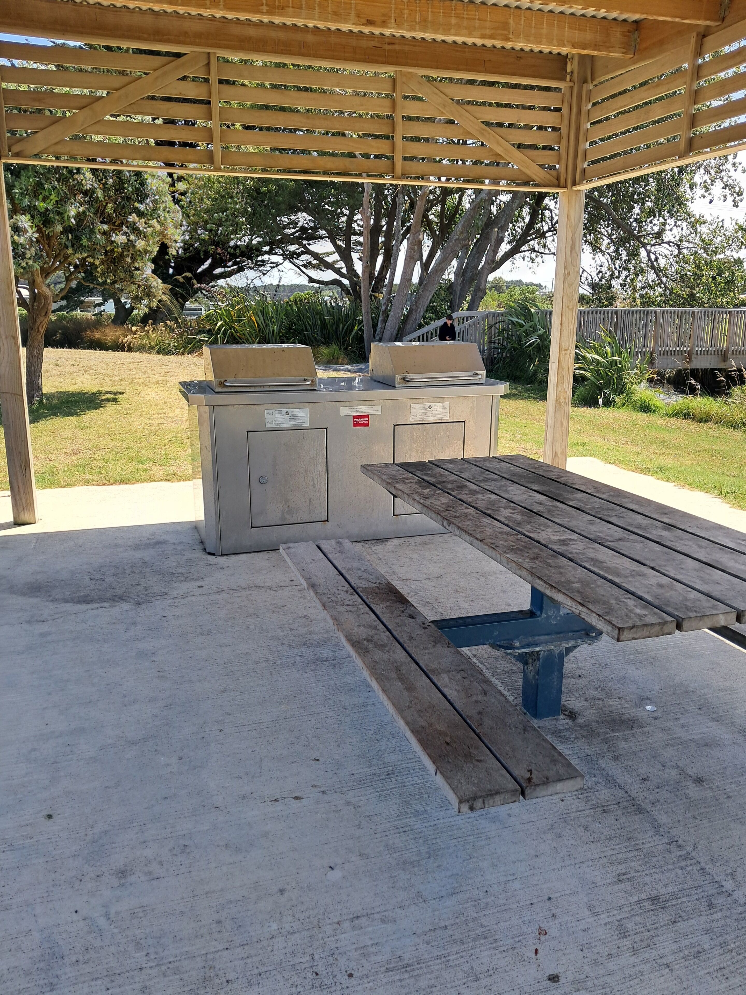 An outdoor barbecue area with a wooden table and grill station.