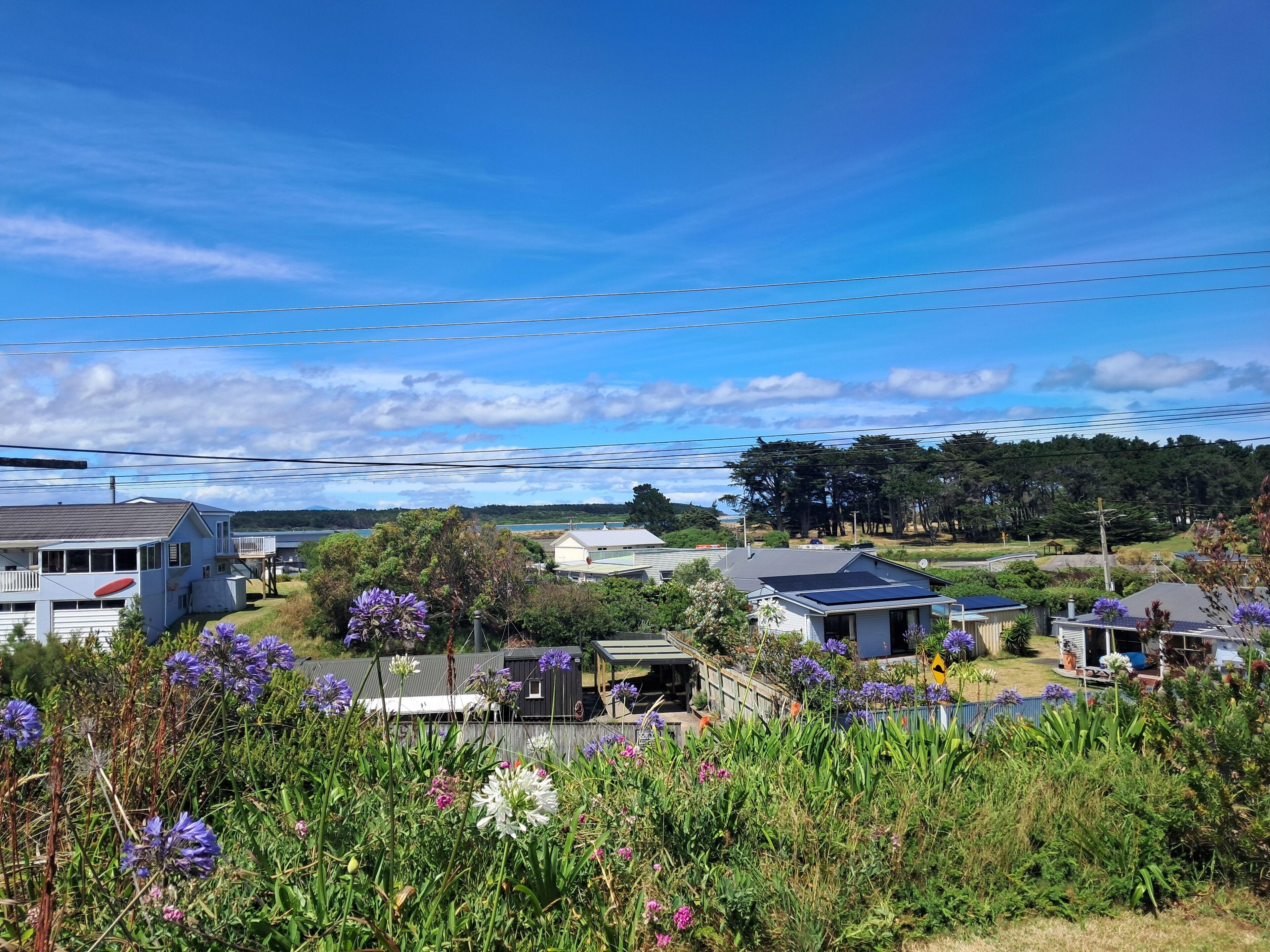 A residential area with houses, a solar panel on one roof, and a view of a natural landscape in the background.