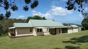 A single-story house with a green roof, a porch, and a small garden area. - Deep Creek Homestead (Deep Creek National Park)