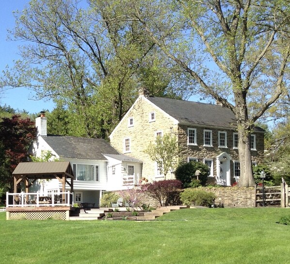 A stone house with a large lawn and a gazebo.