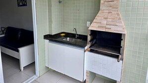 Una cucina compatta con lavandino, un piccolo piano di lavoro e una griglia integrata.