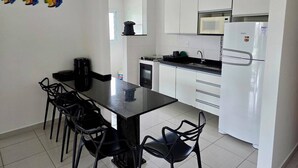 Una cucina compatta con pensili bianchi, un piano di lavoro nero e una macchina da caffè.