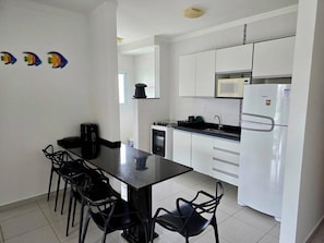 A compact kitchen with white cabinets, a black countertop, and a coffee maker.