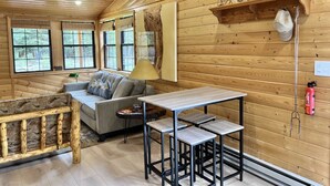 Een gezellig chalet binnen met houten details, een bank, een tafel en een open haard.