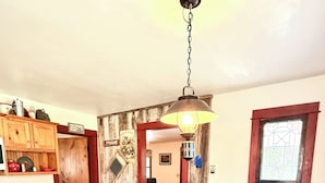 A wooden dining table with chairs, a kitchen area with wooden cabinets, and a hallway leading to another room. - Cottage on Mink River Road  (Ellison Bay)