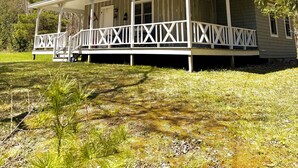 A single-story house with a porch, chimney, and a clear blue sky. - Cottage on Mink River Road  (Ellison Bay)