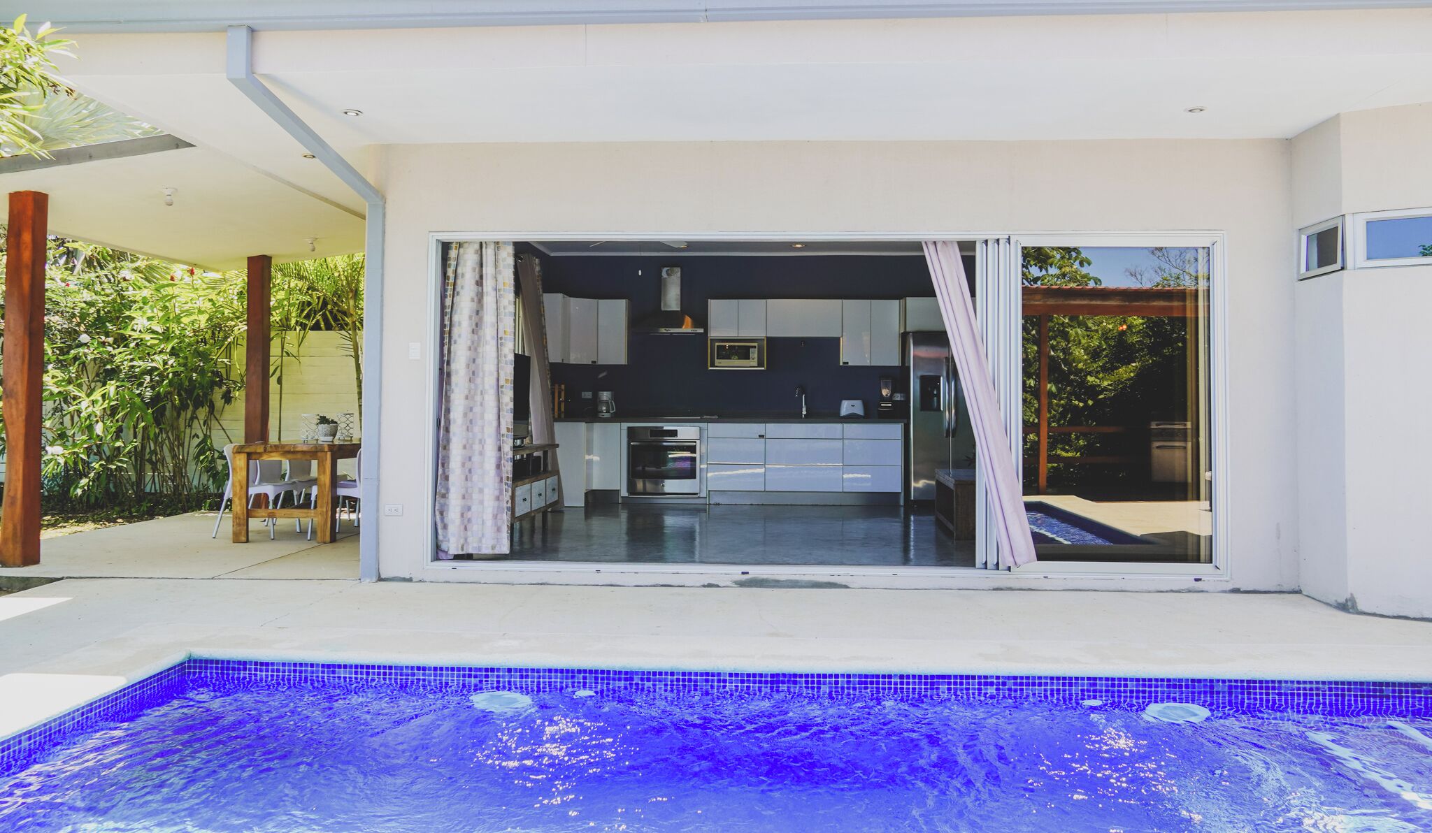 A modern house with a swimming pool, a kitchen, and a patio area.
