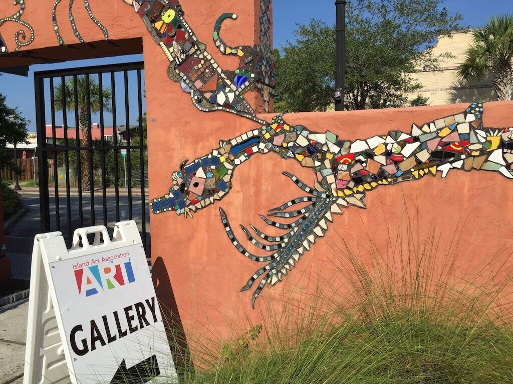 A mosaic wall with a sign for the Island Art Association Gallery.
