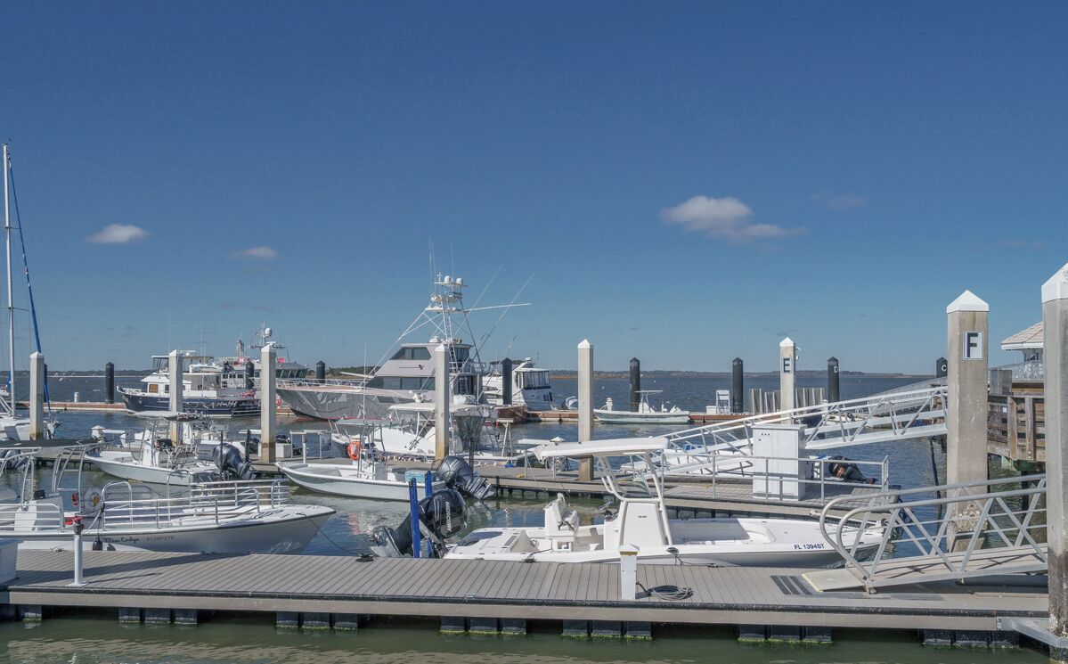A marina with various boats docked, including a large yacht and smaller vessels.