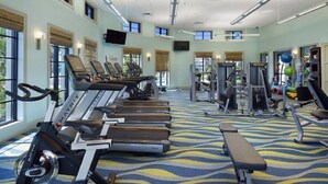 Un gimnasio con cintas de correr, bicicletas estáticas y máquinas de pesas.