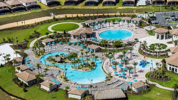 Vista aérea de un complejo turístico con múltiples piscinas, zonas de descanso y edificios.