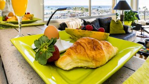 Colazione con un croissant, fragole, una banana e un bicchiere di succo d'arancia su un piatto verde.