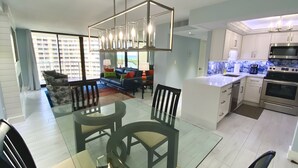 A modern kitchen with stainless steel appliances, a dining area with a glass table, and a living space with a sofa and chairs. - Newly Renovated Beach Condo with 2 Kings...Awesome Pool, Beach and Sunset Views (Marco Island)