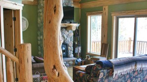 A rustic interior with a large wooden tree trunk centerpiece, wooden flooring, and a stone fireplace. - Bear's Den-Pet Friendly! Close to Ski Cooper.  Private lake access! (Leadville)