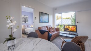 A modern living room with a marble table, leather sofa, and a television. - Jacaranda Apartment | Wayville Walk to Tram (Wayville)