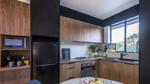 A modern kitchen with wooden cabinets, a built-in microwave, and a gas stove. - Jacaranda Apartment | Wayville Walk to Tram (Wayville)