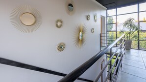 A modern interior with a staircase, a railing, and a series of wall-mounted mirrors. - Jacaranda Apartment | Wayville Walk to Tram (Wayville)