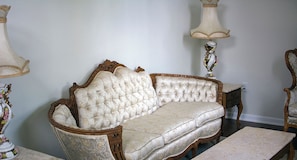 A vintage sofa with ornate wooden carvings, a matching armchair, and a table with a marble top.