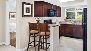 Una cocina moderna con armarios de madera oscura, un microondas integrado y un ventanal que proporciona luz natural.