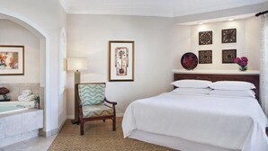 Una habitación de hotel con una cama grande, una silla, un escritorio, una lámpara y un baño con bañera y toallas.
