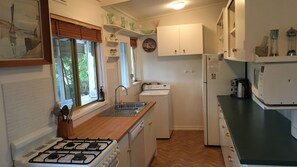 A compact kitchen with a gas stove, sink, washing machine, and a microwave. - Adrift at Ventnor, Pet Friendly on Phillip Island + wifi & linen (Ventnor)