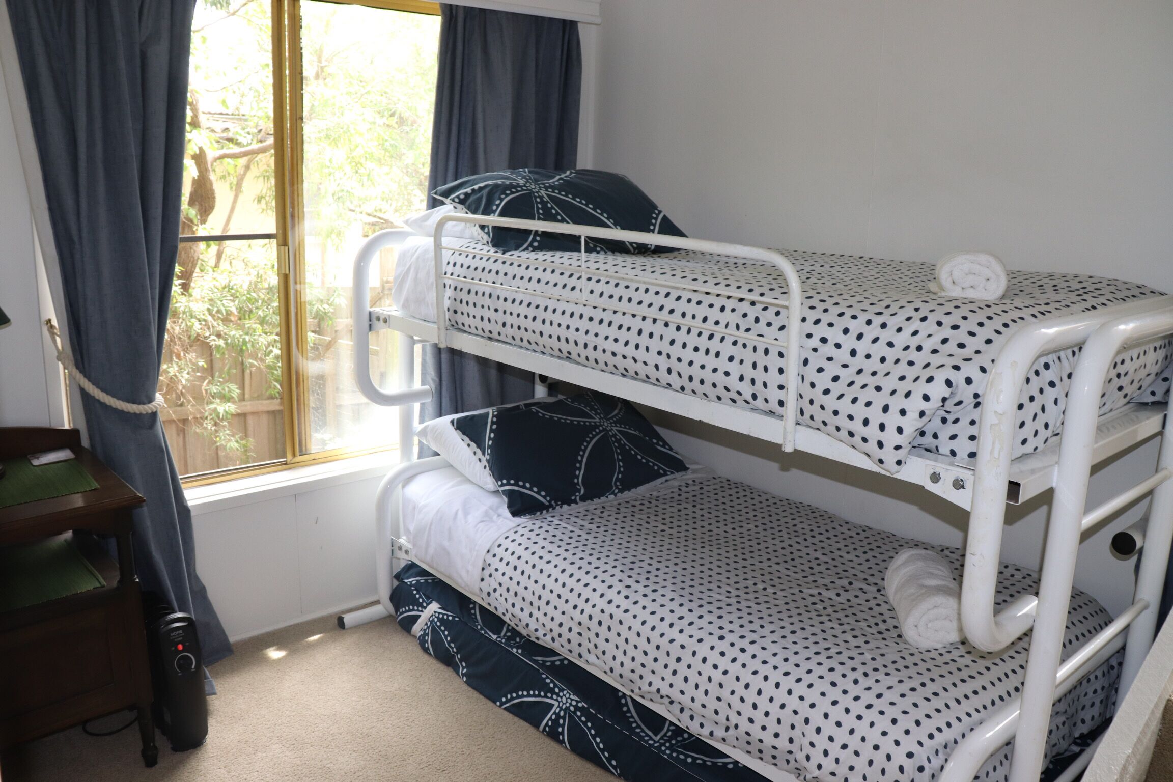 A bunk bed with polka dot bedding, a desk with a chair, and a window with curtains.