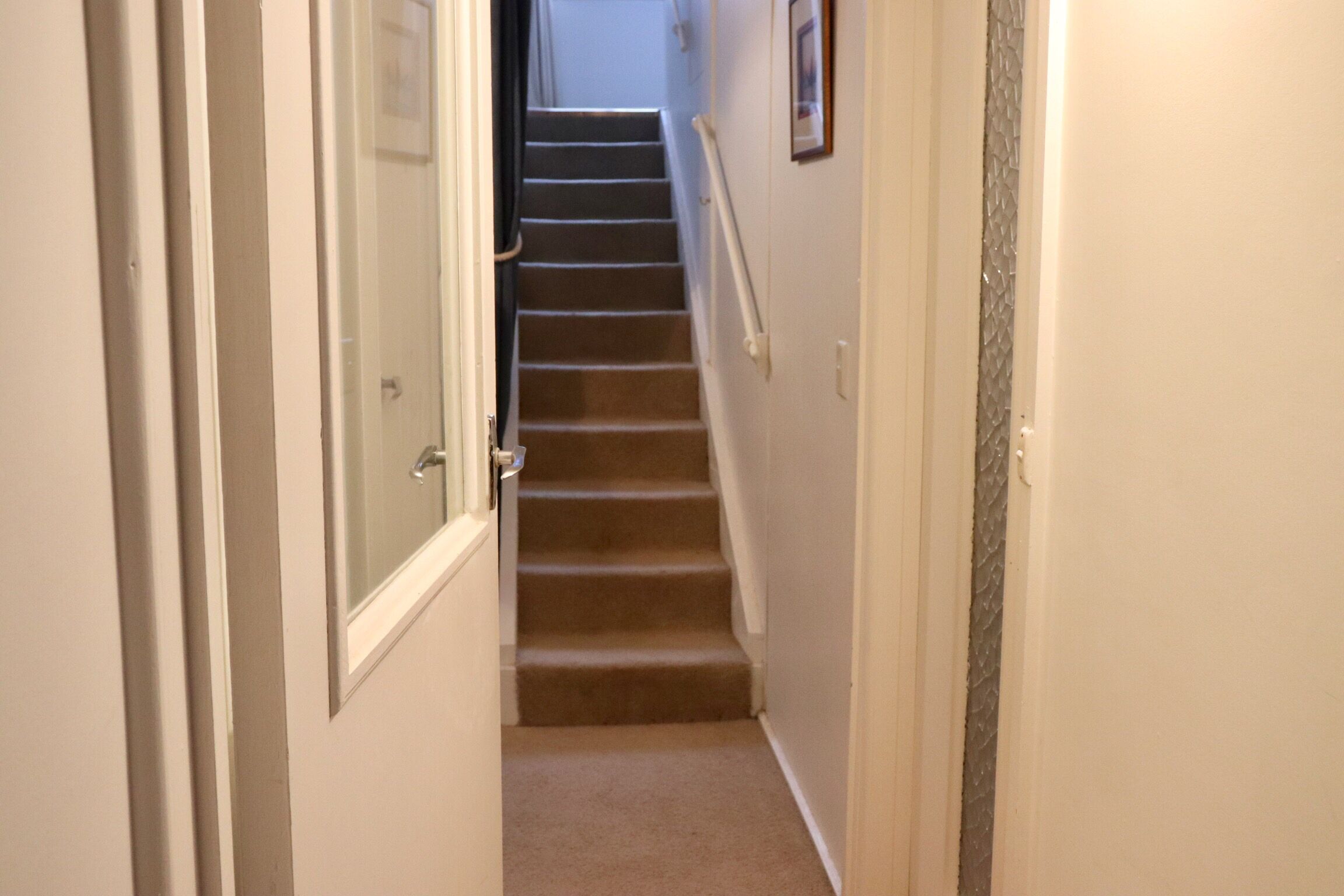 Un escalier recouvert de moquette, doté d’une main courante, qui mène à l’étage supérieur.