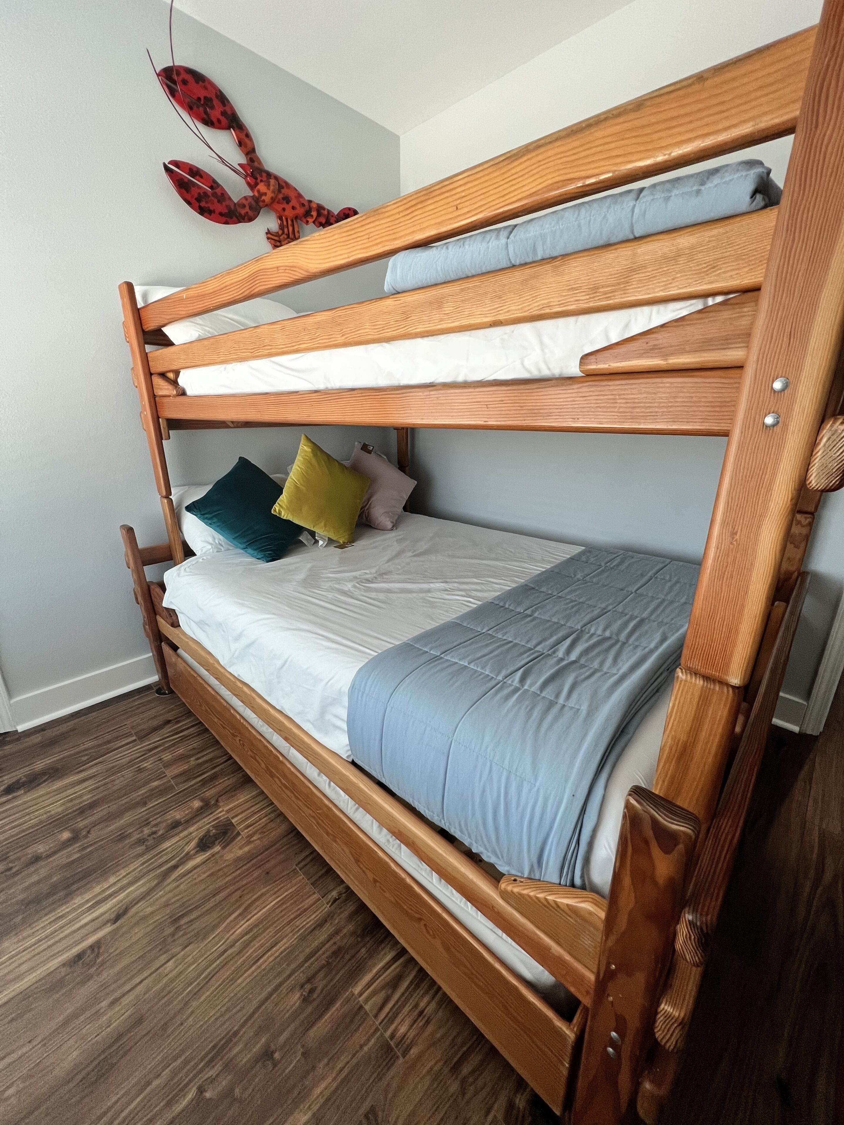 A bunk bed with a wooden frame, two pillows, and a blanket.