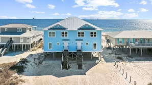 A beachfront house with a central staircase leading to a deck, surrounded by sandy beach and ocean views. - Best Value Modern family friendly gulfront home (Gulf Shores)