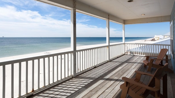 A covered wooden deck with white railings overlooking a beach. - Best Value Modern family friendly gulfront home (Gulf Shores)