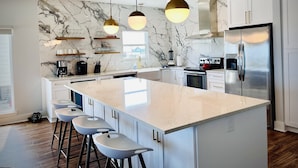 A modern kitchen with marble backsplash, stainless steel appliances, and pendant lighting. - Best Value Modern family friendly gulfront home (Gulf Shores)