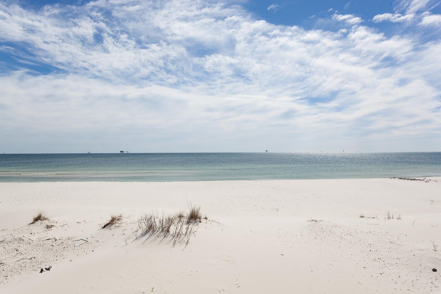 A beach with white sand and a clear sky.