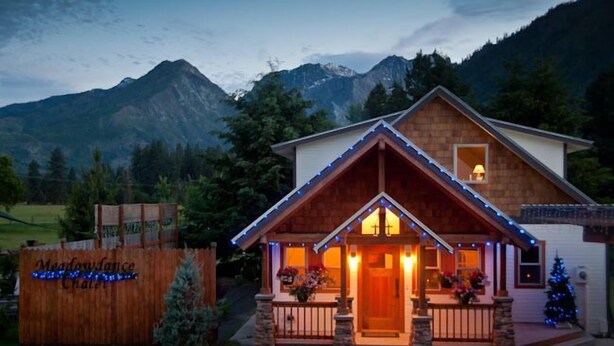 A lodge with a wooden facade, stone pillars, and a porch with string lights. - Expansive Secluded Retreat w/ Hot tub, Mtn Views, 2mi to town, trails, birding (Leavenworth)