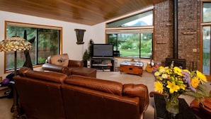 A spacious living room with a large brown leather sofa, a flat-screen TV, and a fireplace. - Expansive Secluded Retreat w/ Hot tub, Mtn Views, 2mi to town, trails, birding (Leavenworth)