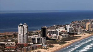 Un paisaje urbano costero con rascacielos, una playa y el océano.