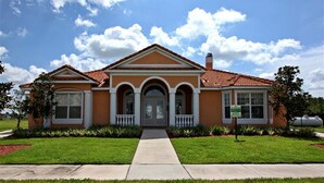 A two-story house with a front porch, a central entrance, and a small garden area. - Cost-Effectiven 8BR/5BA pool home! Near Disney,SeaWorld and Convention Ctr (Kissimmee)