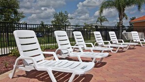 A row of white lounge chairs with metal frames, arranged on a brick patio with a black metal fence in the background. - Cost-Effectiven 8BR/5BA pool home! Near Disney,SeaWorld and Convention Ctr (Kissimmee)