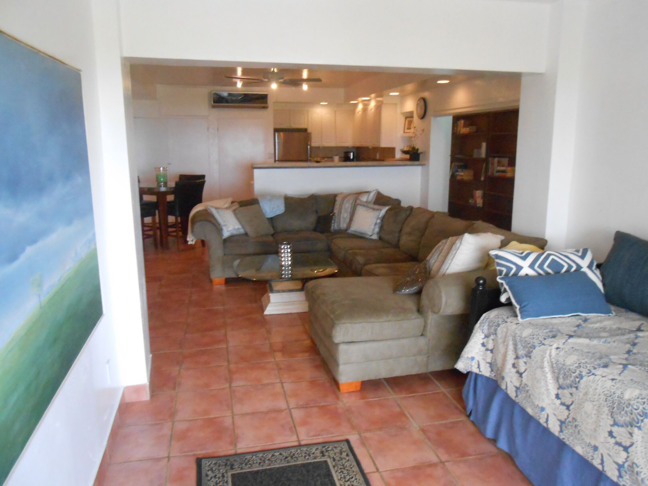 A living room with a sectional sofa, a coffee table, and a dining area in the background.