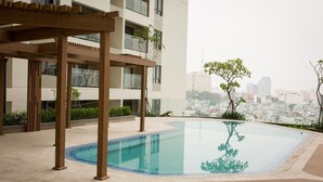 A rooftop swimming pool with a wooden pergola, surrounded by a cityscape view. - Nice Apartment at GoldView (Ho Chi Minh City)