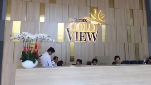 A reception desk with a sign reading "IN THE GOLD VIEW" and a potted plant with white orchids. - Nice Apartment at GoldView (Ho Chi Minh City)