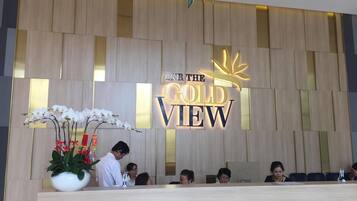 Un comptoir d’accueil avec une pancarte indiquant « IN THE GOLD VIEW » et une plante en pot ornée d’orchidées blanches.
