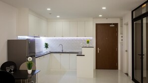 A modern kitchen with white cabinets, a black countertop, and a built-in sink. - Nice Apartment at GoldView (Ho Chi Minh City)