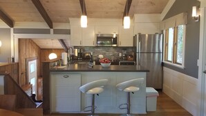 Una cocina moderna con una isla central, electrodomésticos de acero inoxidable y una escalera de madera.
