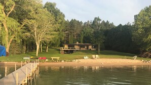 A lakeside property with a wooden dock, a covered picnic area, and a house with a deck. - Beautiful Walloon Lake Home - with Pontoon Boat option. Sept & Oct availability! (Petoskey)