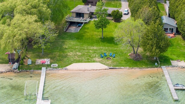 An aerial view of a residential property with a large lawn, a swimming pool, and a dock extending into the water. - Beautiful Walloon Lake Home - with Pontoon Boat option. Sept & Oct availability! (Petoskey)