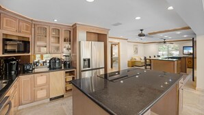 A modern kitchen with built-in appliances, a large island, and a dining area with a view. - Elegant Home with Beach & Dockage! Spectacular Sunsets! (Key Largo)