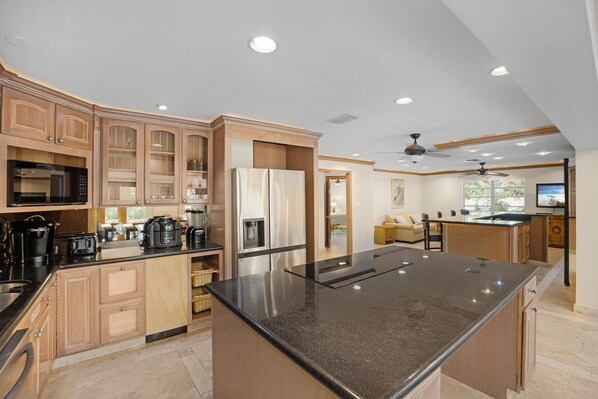 A modern kitchen with built-in appliances, a large island, and a dining area with a view.