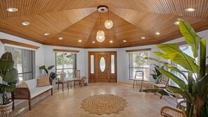 A spacious room with a wooden ceiling, large windows, and a central door. - Elegant Home with Beach & Dockage! Spectacular Sunsets! (Key Largo)