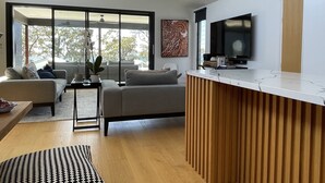 Una sala de estar moderna con un sofá, una mesa de centro y un televisor montado en la pared.